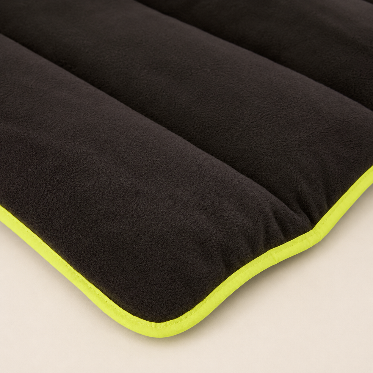 Close-up of the 3 Peaks Roll Up Travel Dog Mat black fleece padding and bright lime edge trim