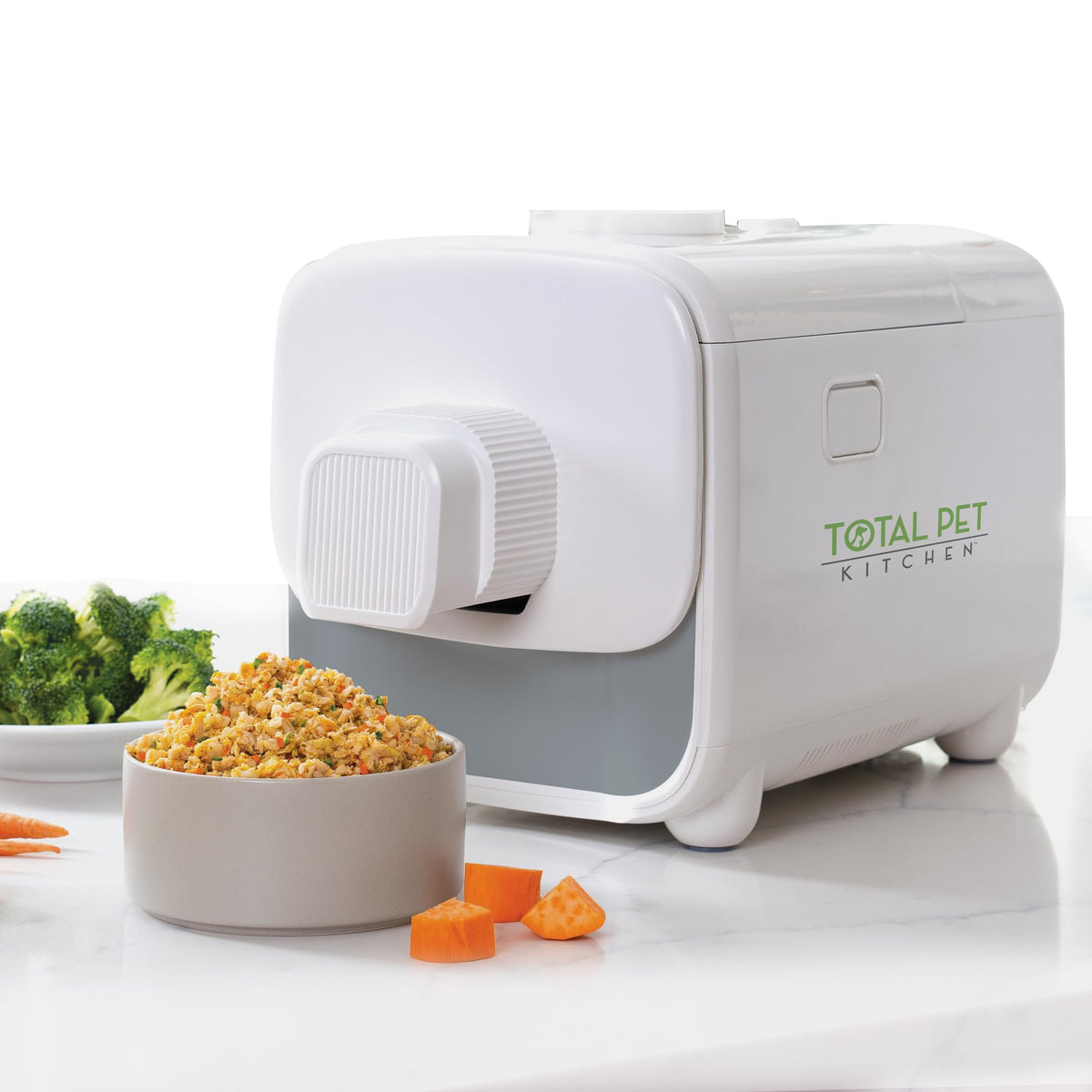 Total Pet Kitchen pet food maker on a kitchen counter beside a bowl of prepared food and fresh vegetables