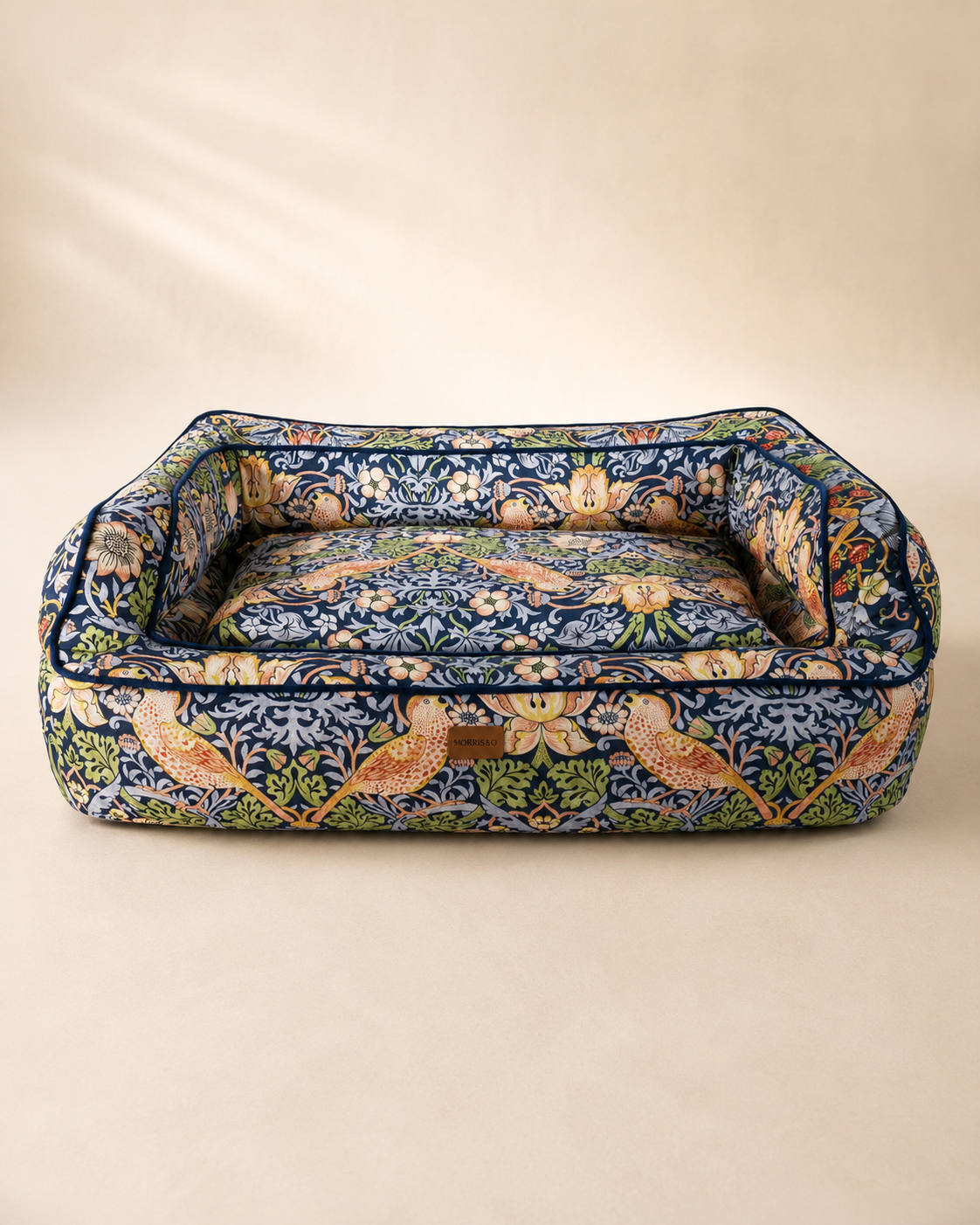 Morris & Co Strawberry Thief pet sofa bed in navy floral print on a warm neutral background